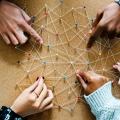 Ein Netz aus Fäden, gespannt mit Pins. Mehrere Hände zeigen auf Pins und Verbindungen / Curated lifestyle auf unsplash.com.